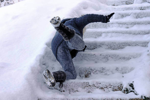A person falls face first on a set of icy stairs.